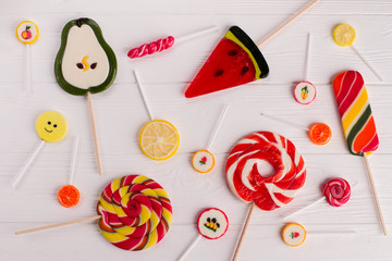 Composition with tasty colorful candies on wooden background. Mixed colorful lollipops on white wood.