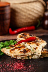 The concept of Georgian cuisine. Baked pita with suluguni cheese and cilantro. Serving dishes on a black stone slate. On a wooden background. copy space