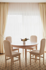 Bright spacious dining room with wooden  table, four chairs and big window