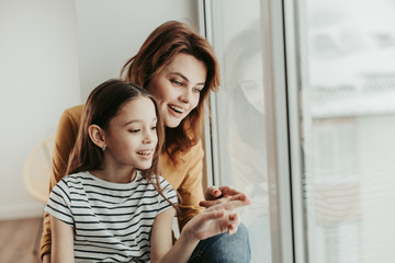 Mother and daughter curiously looking at window