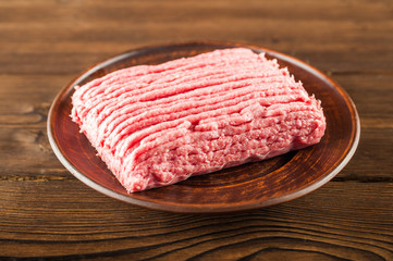 Chicken mince on a wooden plate on a textured table. Turkey mince raw close-up and copy space.