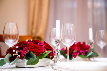 2 floral arrangements of red roses and carnations for table decoration (wedding, restaurant) on a server table, table setting