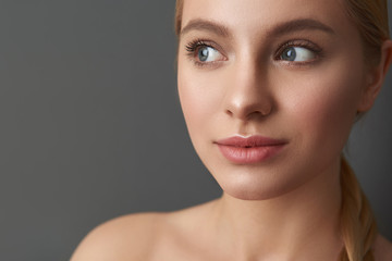 Fototapeta premium Close up of curious lady with bare shoulders standing and smiling