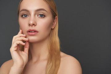 Fototapeta premium Long haired woman standing with bare shoulders and looking thoughtful