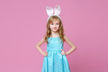 Obraz na płótnie Canvas Beautiful blonde in the shape of an Easter Bunny and a blue dress with a pea pattern holds her hands at the waist. Concept of advertising and fashion. Happy Easter. Selective focus.