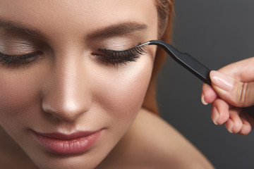 Pleased woman smiling and getting beautiful fake eyelashes