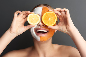 Funny woman putting slices of lemon and orange on her eyes and smiling