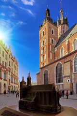 Fototapeta na wymiar Market square and St. Mary's Basilica in Krakow, Poland in stunning sunset sun light. People tourists walking down the street and relaxing