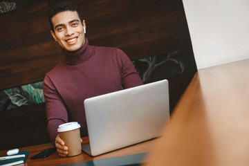 Handsome afro american guy with hot drink using laptop