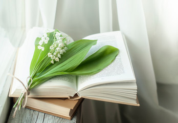 book and spring flowers, lilies of the valley on a wooden background. Reading a book or education.