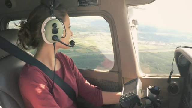 Gorgeous model piloting a small private plane looking around and smiling
