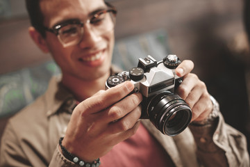 Young man looking at retro camera and smiling