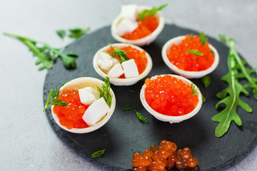 Red caviar on black plate with spoon and creamy cheese. Food photo concept