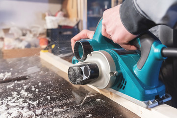 The hands of a carpenter working woodworking power tools. Close up of the work of the electric...