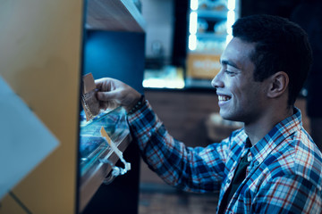 Handsome young man in plaid shirt buying in the store