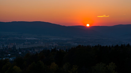 Landscape with the sunset. Clear orange sky with little cloud and dark landscape.