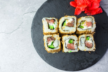 Sushi rolls with salmon, vegetables, ginger on black background. Japanese food, sea food concept