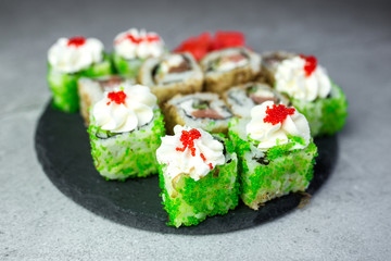 Sushi rolls with salmon, vegetables, ginger on black background. Japanese food, sea food concept