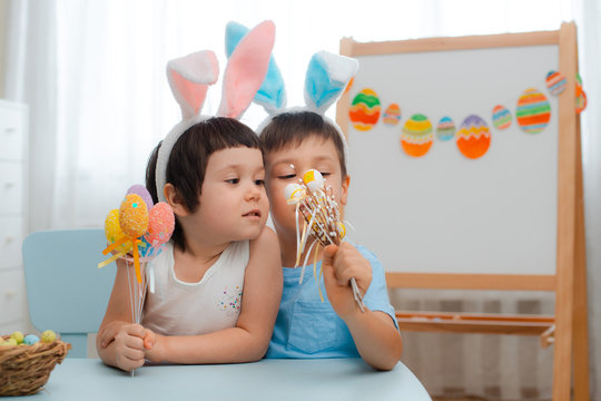 Little boy and girl in bunny ears are playing with Easter eggs. Kids celebrating Easter. Children on Easter egg hunt. Home decoration, pastel bunny banner. brother and sister give a bouquet