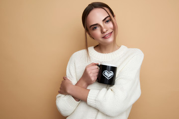 Waist up of cute lady in sweater standing with beautiful cup