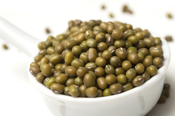 Closeup of mungo beans in a white spoon  on white background