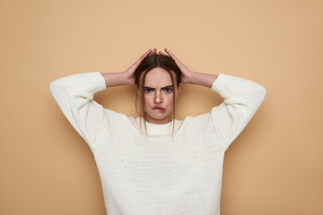 Young woman frowning and putting hands on her head