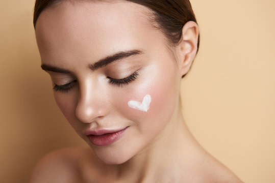 Portrait of peaceful young lady with makeup and heart picture on face