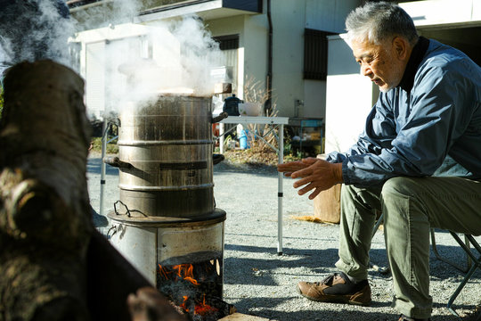 An Older Asian Man Warming Himself Up