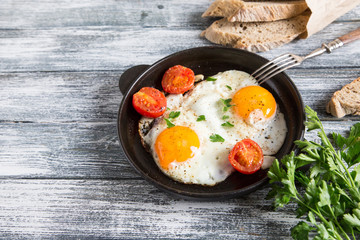 Fried egg. Close up view of the fried egg on a frying pan with cherry tomatoes and parsley