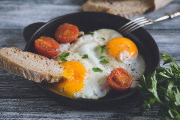 Fried egg. Close up view of the fried egg on a frying pan with cherry tomatoes and parsley