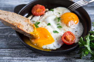 Fried egg. Close up view of the fried egg on a frying pan with cherry tomatoes and parsley