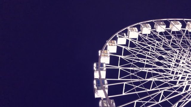 Ferris wheel. High luminous carousel on a dark background. Evening video. Blue background