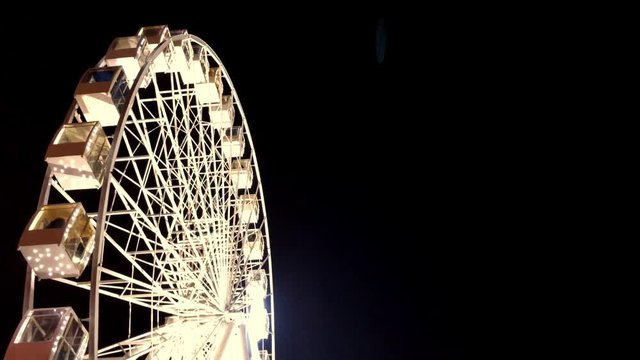 Ferris wheel. High luminous carousel on a dark background. Evening video. Black background