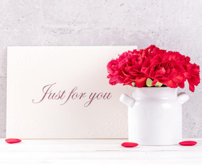 May mothers day handmade giftbox wishes photography - Beautiful blooming carnations with red ribbon box isolated on fair-faced gray background desk, close up, copy space, mock up
