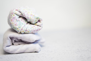Colorful cotton folded clothes stack on white table empty space background,baby laundry.