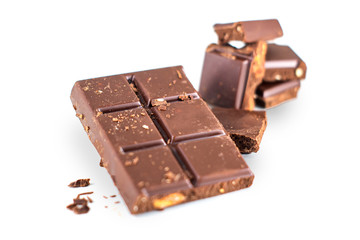 broken chocolate and hazelnuts on isolated white background.