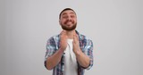 Excited young man cheering and clapping on white background