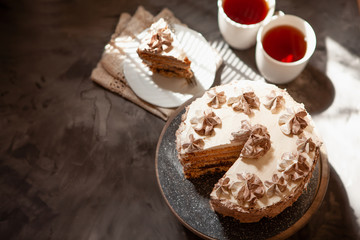 Homemade Kiev cake, dacquoise cake with butter cream, hazelnuts and tea cups top view