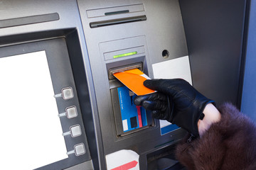 Hand of a woman with a credit card, using an ATM.