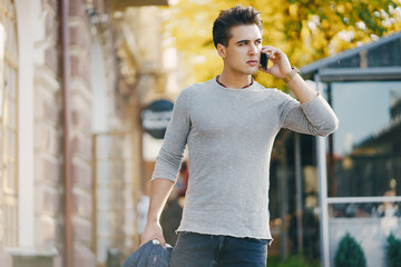 stylish man using his phone while walking through the city by himself