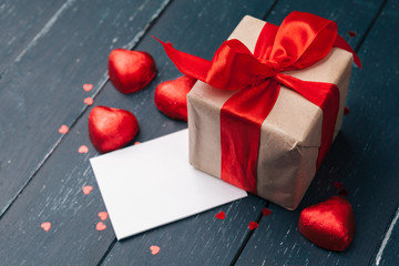 Gift box with red hearts on wooden table