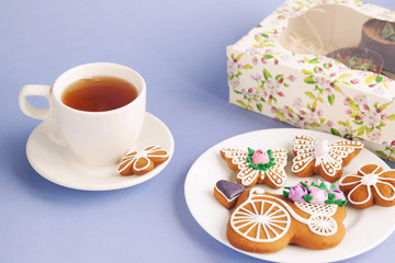 Homemade gingerbread, spring provence. Mother's Day. Sweet flowers, butterflies, a Sweet flowers, butterflies, a bicycle, and tea on the table. Lilac background.