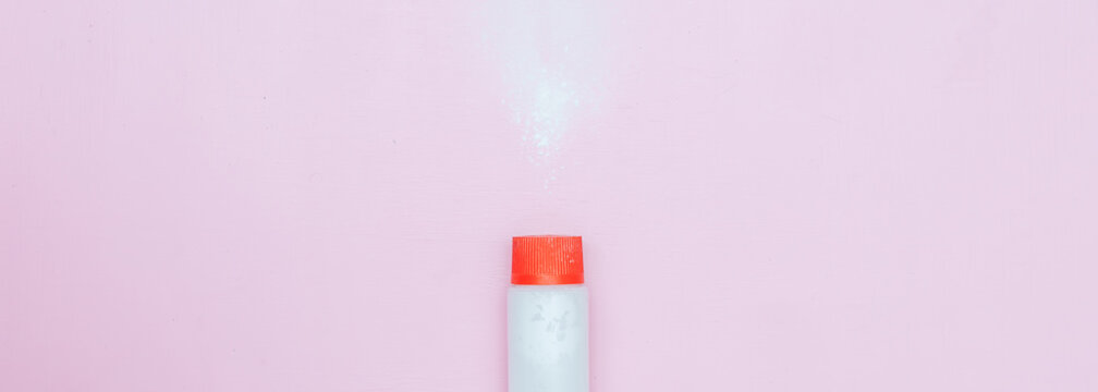 Bottle Of Talcum Baby Powder On Pink Background. Powder Spilled From White Container, Top View Flatlay Long Banner