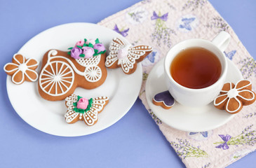 Homemade gingerbread, spring provence. Mother's Day. Sweet flowers, butterflies, a Sweet flowers, butterflies, a bicycle, and tea on the table. Lilac background.