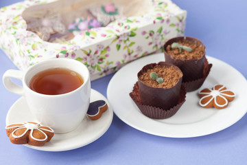 Homemade gingerbread, spring provence. Mother's Day. Sweet flowers, butterflies, a Sweet flowers, butterflies, a bicycle, and tea on the table. Lilac background.