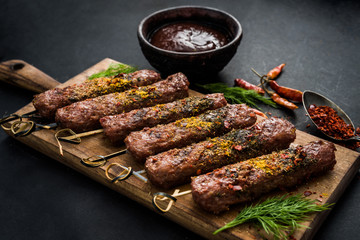 Grilled kebab with spices and sauce on a dark background