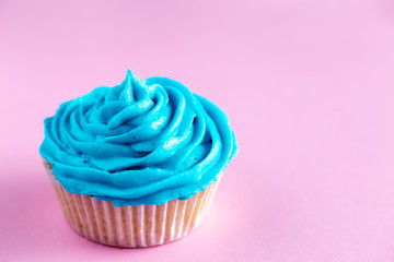 Cupcake with blue icing on a pink worktop