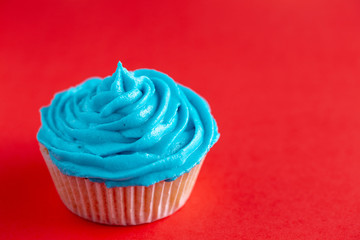 Cupcake with blue icing on a red worktop