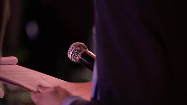 presenter with microphone and folder performs on stage