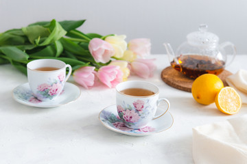 Afternoon tea with cake, lemon, teapot and tulips on the background. Tea party. Spring mood, Mother's day concept. Copy space